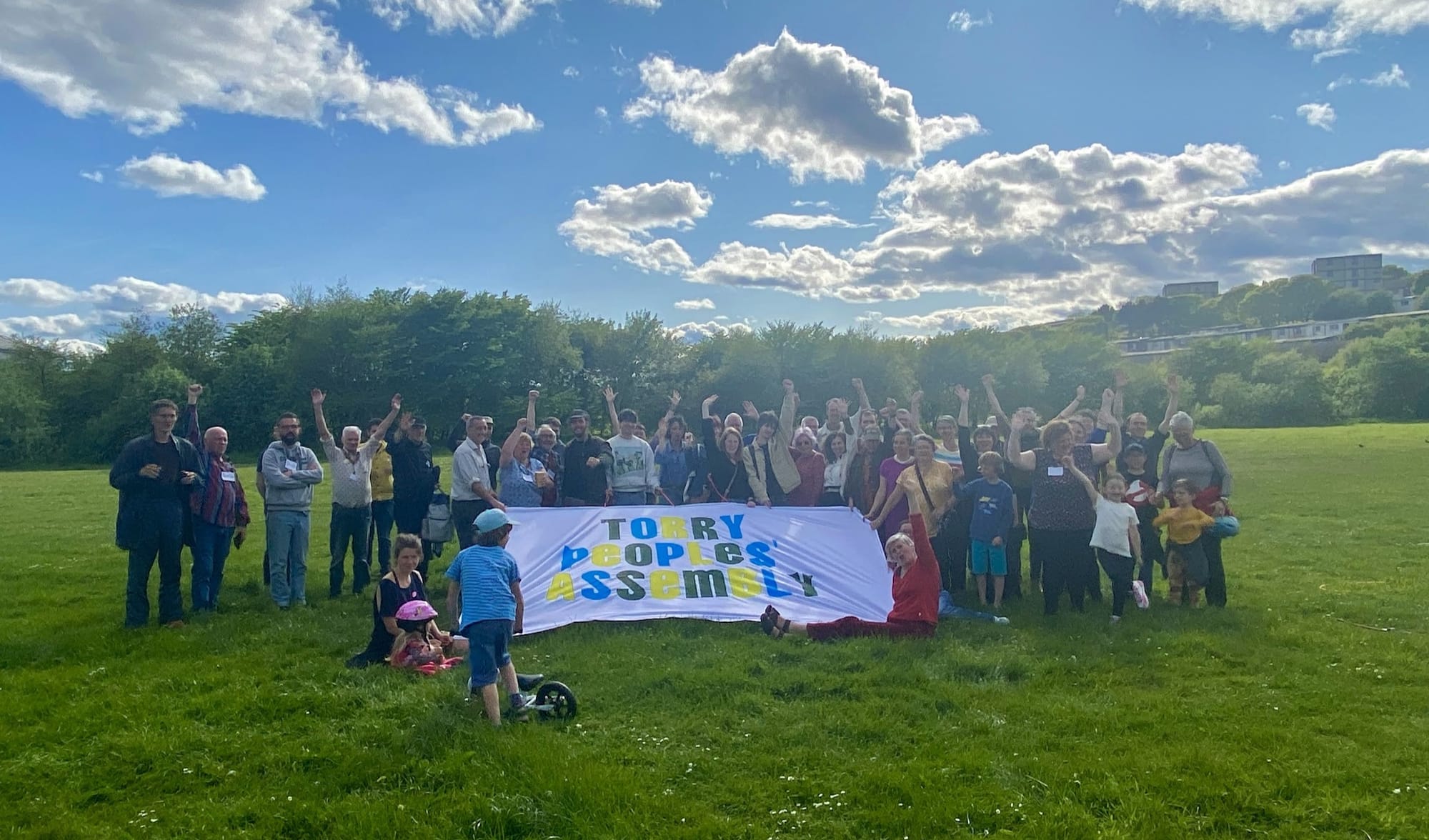 Group of people in a green area holding a big "Torry Peoples' Assembly" sign