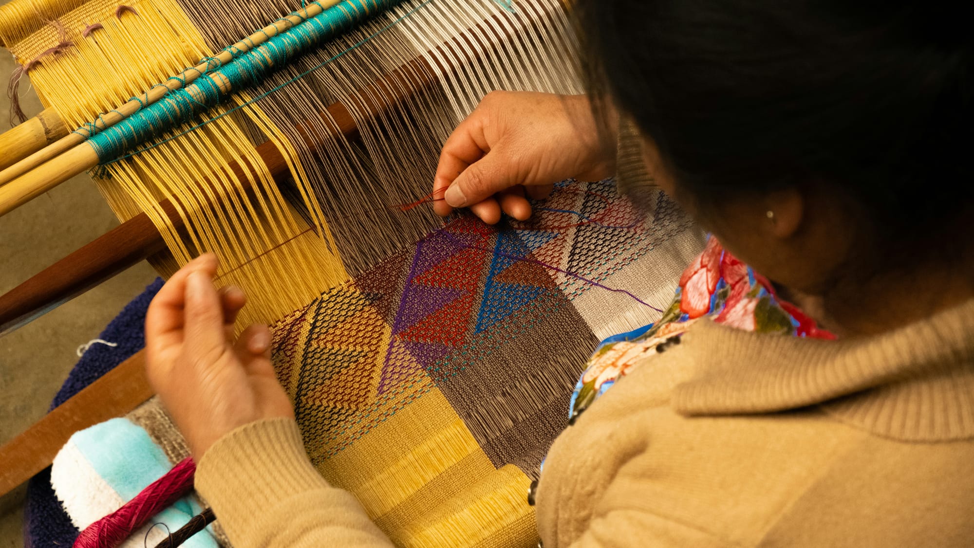 Indigenous elder weaving a coloured tapestry