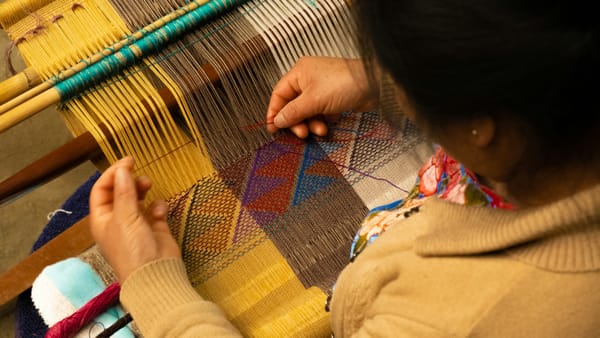 Indigenous elder weaving a coloured tapestry
